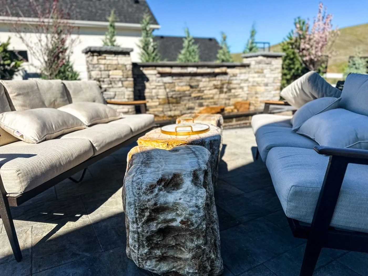 Outdoor sofas around boulder side tables in front of a stacked-stone wall