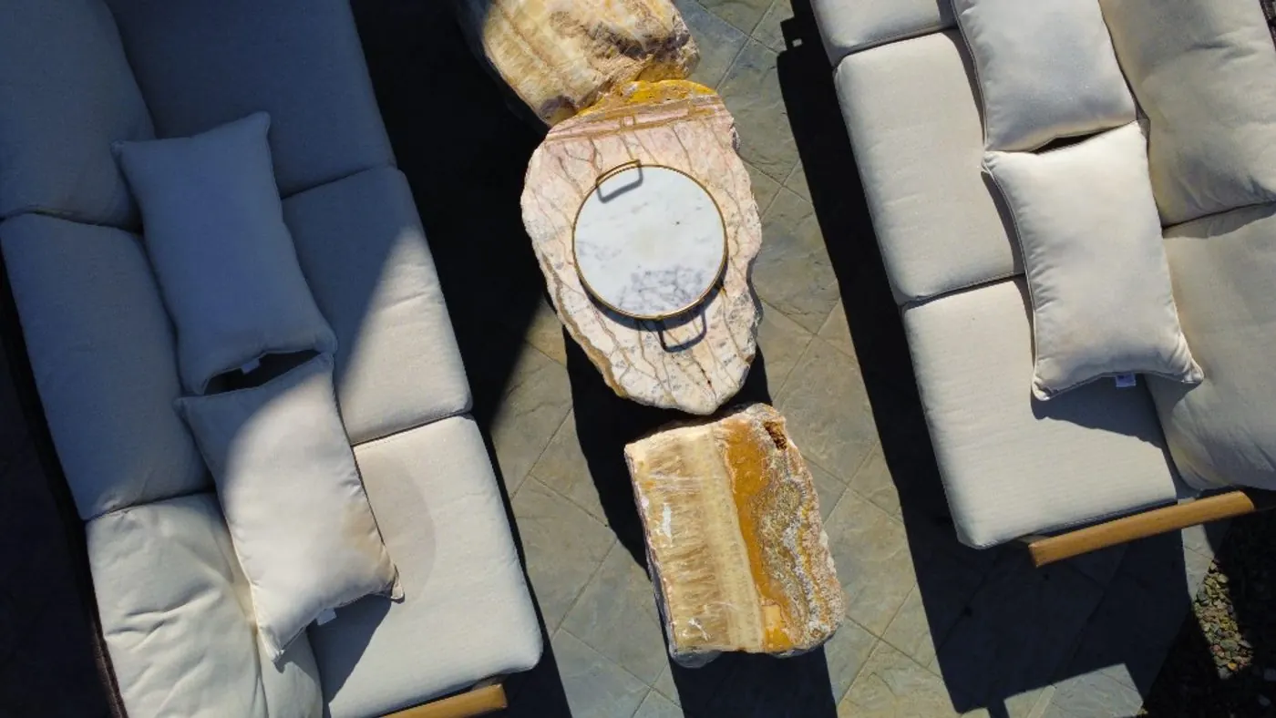 Overhead view of amber and white onyx boulder tables between two cream-cushioned sofas on the paver patio