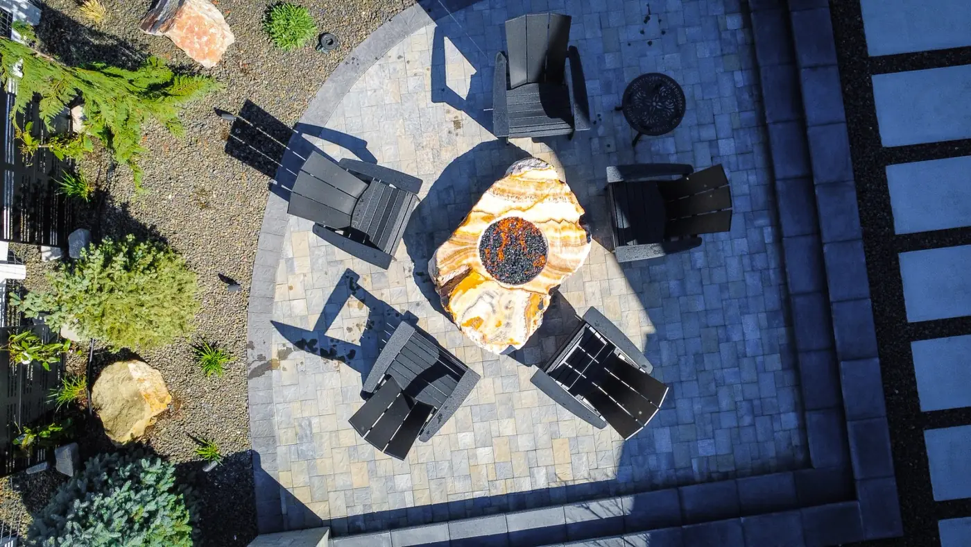 Looking down on a circular paver patio with a boulder fire pit and chairs, as a plan view
